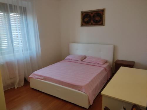 a bedroom with a bed with pink sheets and a window at Attico in Pitigliano