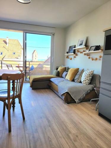 un salon avec un canapé et une grande fenêtre dans l'établissement Appartement au coeur du Village avec terrasse, à Wattwiller