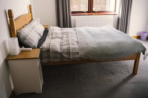 a bedroom with a bed with a night stand and a table at 3-bedroom house for outdoor holidays in Alyth