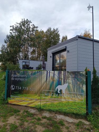 a building with a sign in front of a fence at Wilcza Przystań in Borzygniew