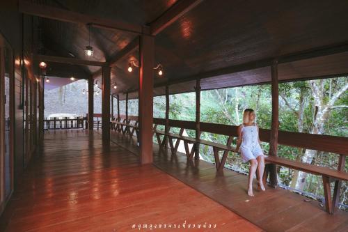 a woman in a white dress standing on a porch at บ้านเคียงธาร โฮมสเตย์ แม่แมะ Cascade Lodge in Amphoe Chiang Dao