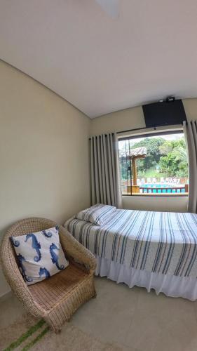 a bedroom with a bed and a chair and a window at Diver Village Ilhabela in Ilhabela