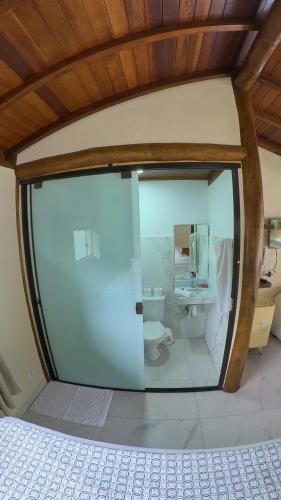 a bathroom with a toilet through a glass door at Diver Village Ilhabela in Ilhabela