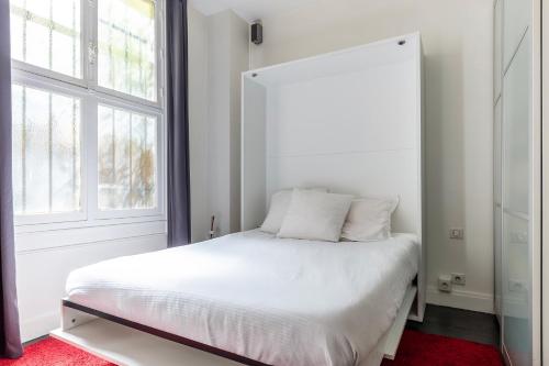une chambre avec un lit blanc et une fenêtre dans l'établissement Studio sur les quais de Seine, à Paris