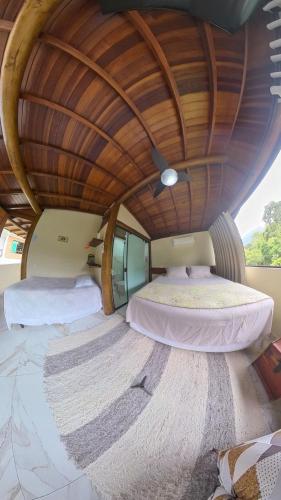 two beds in a round room with a wooden ceiling at Diver Village Ilhabela in Ilhabela