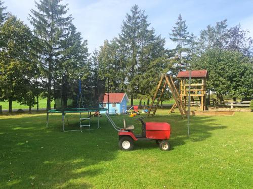 einen Park mit einem Spielplatz mit einem roten Karren im Gras in der Unterkunft Ostseebauernhof Familie Jäger in Tarnewitzerhagen