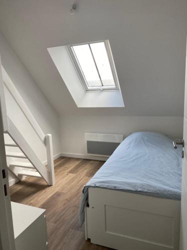 - une chambre blanche avec un lit et une lucarne dans l'établissement La Bôloise, à La Baule
