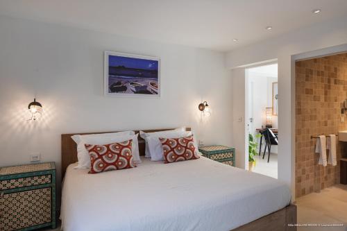 een slaapkamer met een groot wit bed met kussens bij On the Beach , in Saint Barth... Mellow Mood Villa in Saint Barthelemy