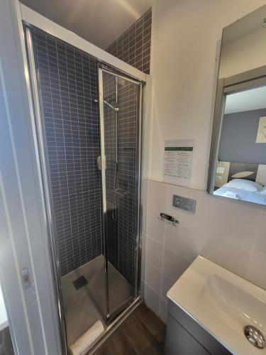 a bathroom with a shower and a sink and a mirror at Hotel Bellevue in Hendaye