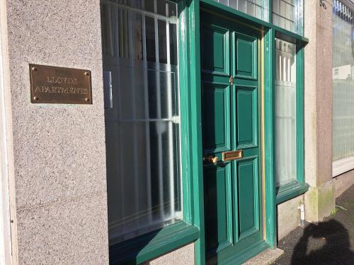 Una puerta verde en un edificio con un cartel. en Lloyds Penthouse, en Tavistock
