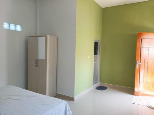 a bedroom with green walls and a bed and a door at Maria Guesthouse in Mandati