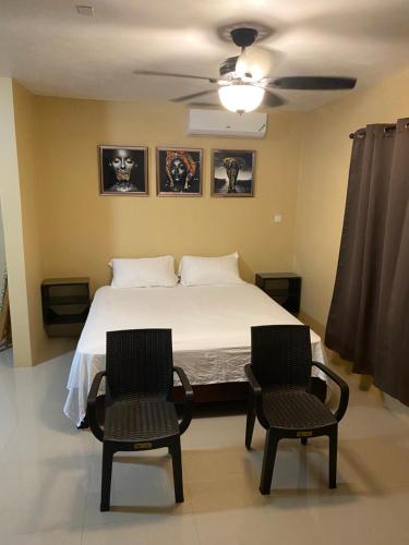 a bedroom with a bed and two chairs at Marshan villa in Montego Bay