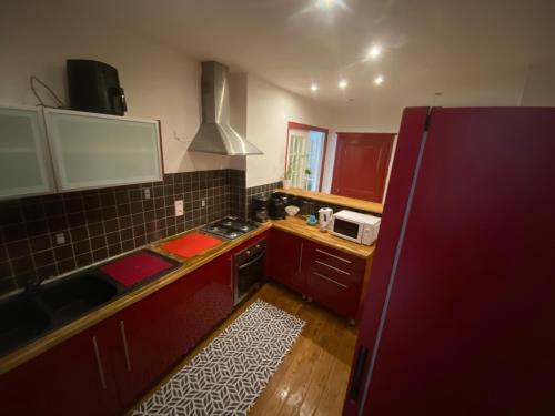 une petite cuisine avec des placards rouges et un four micro-ondes dans l'établissement Mouss, à Joinville