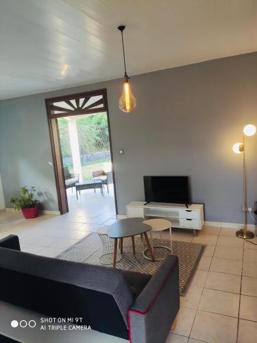 a living room with a couch and a tv at Maison du Lac - jusqu'à 4 personnes in Rémire-Camp