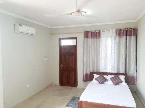 a bedroom with a bed and a wooden door at Spacious Holiday Let Wi-Fi & Private Amenities Oyibi in Oyibi