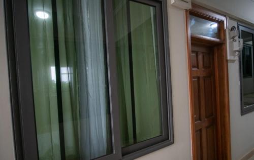 a window with green curtains next to a door at Spacious Holiday Let Wi-Fi & Private Amenities Oyibi in Oyibi