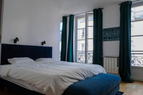 une chambre avec un grand lit et deux fenêtres dans l'établissement Luxurious Apartment in Marais, à Paris