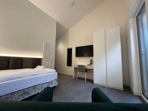 1 dormitorio con 1 cama, escritorio y TV en GreenLeaf Regensburg I Sinzing, en Sinzing