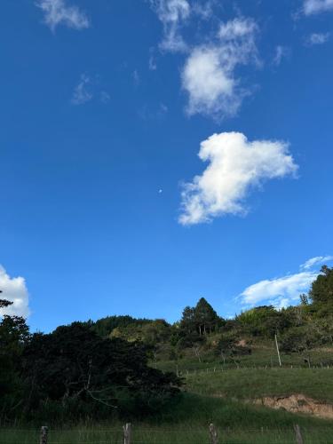 a blue sky with clouds above a field at Habitaciones Alpes Oxapampa in Oxapampa
