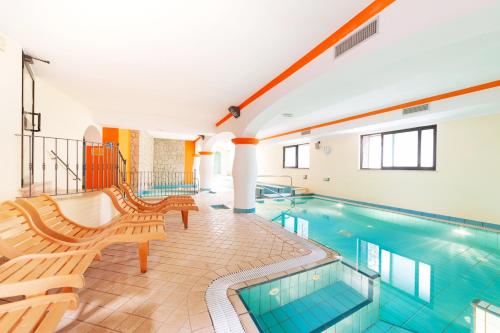 a swimming pool with two benches and a bench at Poggio Aragosta Hotel & Spa in Ischia