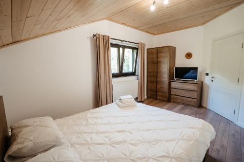 a bedroom with a large white bed and a television at Green Garden in Borşa