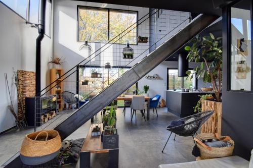 an industrial loft with a staircase and a dining room at Grande chambre couple possible avec sanitaire complet privatif moderne proche Zénith-Atlantis in Saint-Herblain