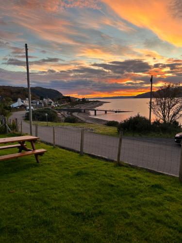 a sunset over a body of water with a picnic table at Seaview in Glenelg