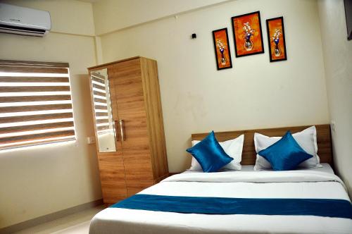 a bedroom with a bed with blue pillows and a window at MARHABA PALACE in Kozhikode