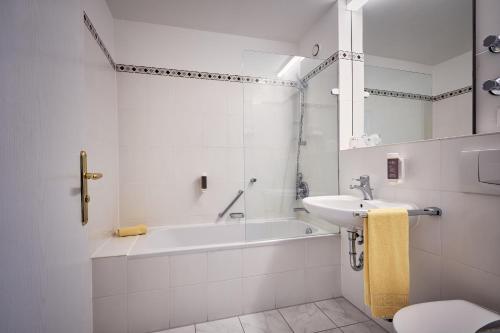 biała łazienka z wanną i umywalką w obiekcie MY Parkhotel w mieście Kempten