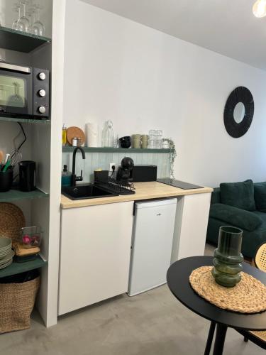 une cuisine avec des armoires blanches, une table et un canapé dans l'établissement Logement de charme Toulouse, à Toulouse