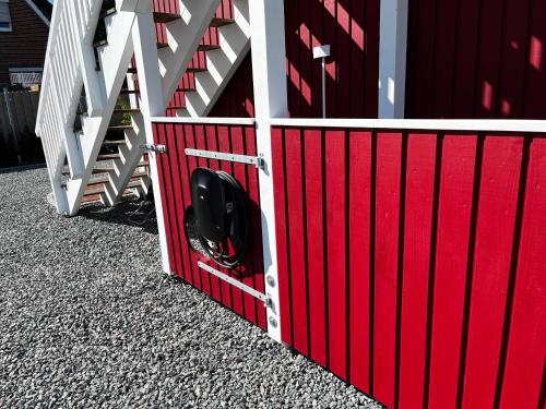 a red and white gate with a wheel in it at Muggelhuus das Ferienhaus im Alten Land / Pflaumenbaum in Twielenfleth