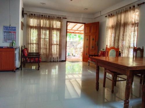 uma sala de estar com uma mesa de madeira e uma porta em Villa Charumathi em Matara