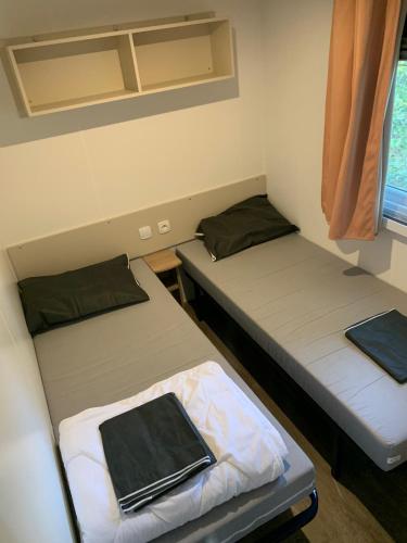 deux lits dans une petite pièce avec une fenêtre dans l'établissement CHEZ PHIL, à Gastes