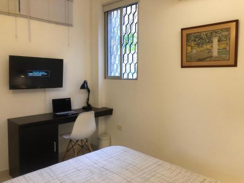 a bedroom with a desk with a computer and a window at Cabañas Annapurna in Taganga