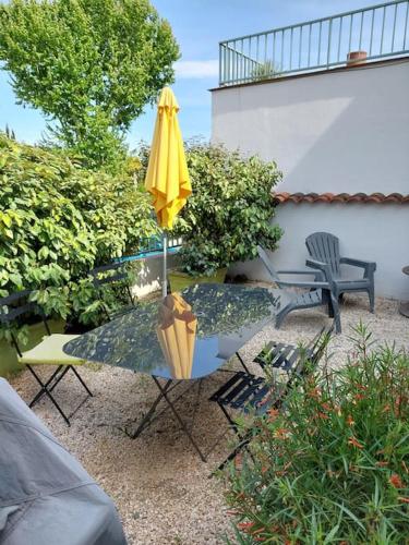 une terrasse avec une table, un parasol et des chaises dans l'établissement L'appartement, au Pradet
