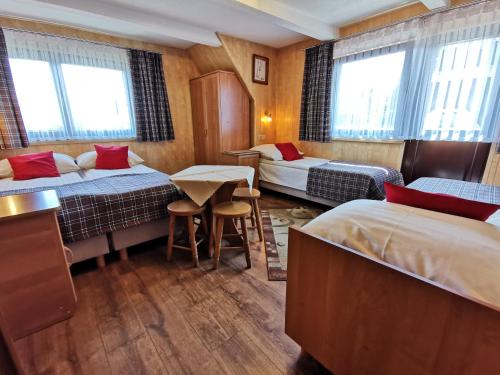 Cette chambre comprend 3 lits, une table et des chaises. dans l'établissement Pokoje Gościnne ZYNGRA, à Poronin