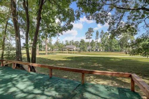 a wooden bench sitting under a tree in a park at Golf course view vacation home in The Woodlands