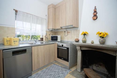 a kitchen with a fireplace with a microwave and a stove at Casa do Outeiro in Meda