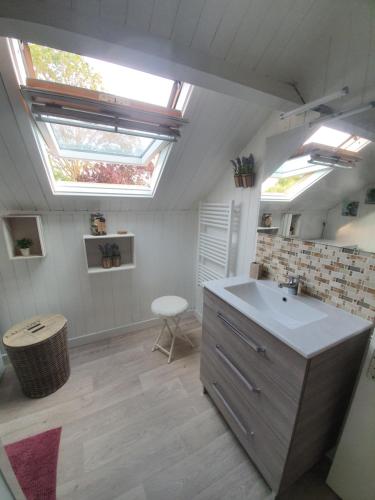 ein Badezimmer mit einem Waschbecken und zwei Oberlichtern in der Unterkunft Chalet à Cabourg in Cabourg