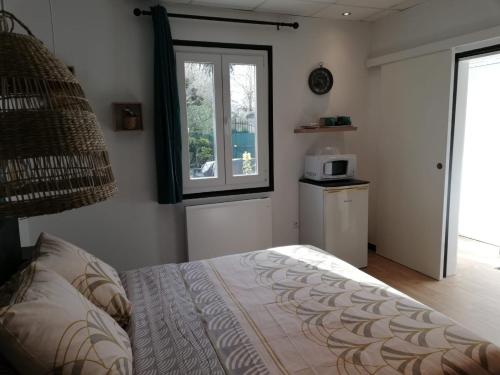 a bedroom with a bed and a window and a microwave at Studio, petit déjeuner inclus, 20min Beauval in Faverolles-sur-Cher