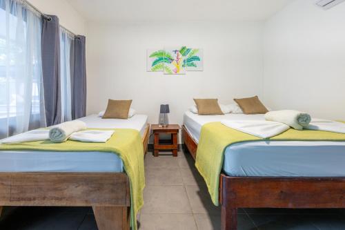 two twin beds in a room with a window at La Casona Eco-Lodge Tortuguero in Tortuguero