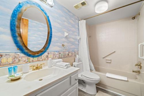 a bathroom with a sink and a toilet and a mirror at Reflections on the Gulf #503 Beachfront Condo with Pool and Hot Tub in Clearwater Beach