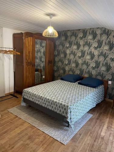 a bedroom with a bed with blue pillows at La maison du sabotier in Oradour-Saint-Genest