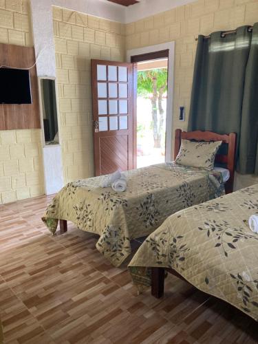 a bedroom with two beds and a door to a patio at Pousada Vitória in Pitimbu