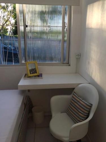 uma cadeira branca sentada em frente a uma janela em República Descolada em Florianópolis