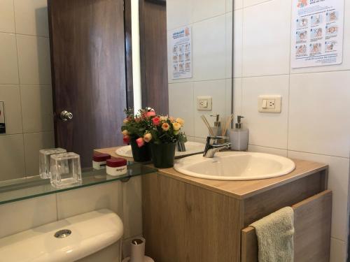 a bathroom with a sink and a toilet with flowers at Cabañas Annapurna in Taganga