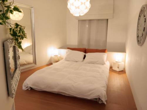 a bedroom with a bed with white sheets and pillows at The Luxury White Suite in Charleroi