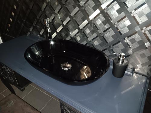 a black sink on a blue counter in a bathroom at The Luxury White Suite in Charleroi