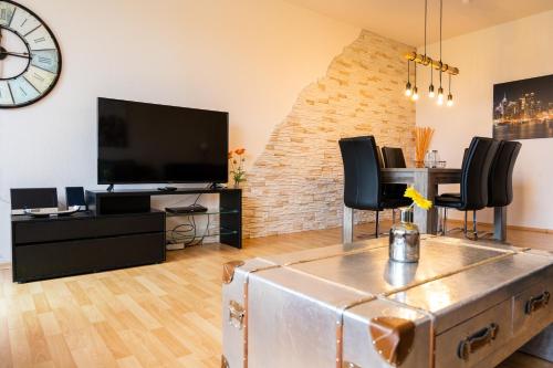 ein Wohnzimmer mit einem TV, einem Tisch und Stühlen in der Unterkunft Art City Studio Kassel 2 in Kassel