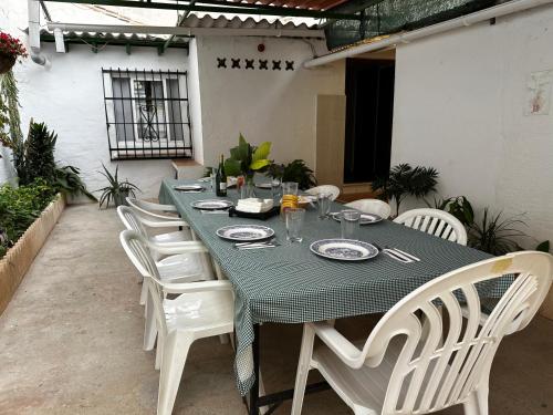 einen Tisch mit weißen Stühlen und einem grünen Tischtuch in der Unterkunft Villa Remedios in Torremolinos